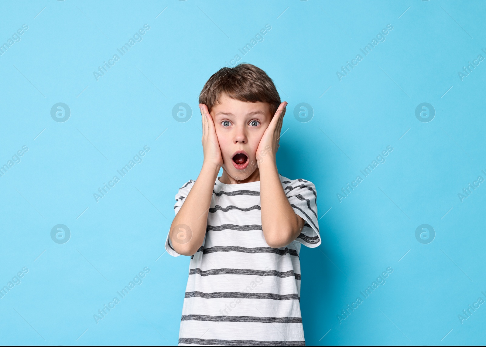 Photo of Scared little boy on light blue background