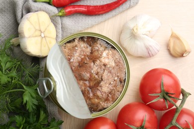 Photo of Canned meat in tin can and other products on wooden table, top view