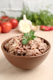 Photo of Canned meat with parsley in bowl on wooden table, closeup