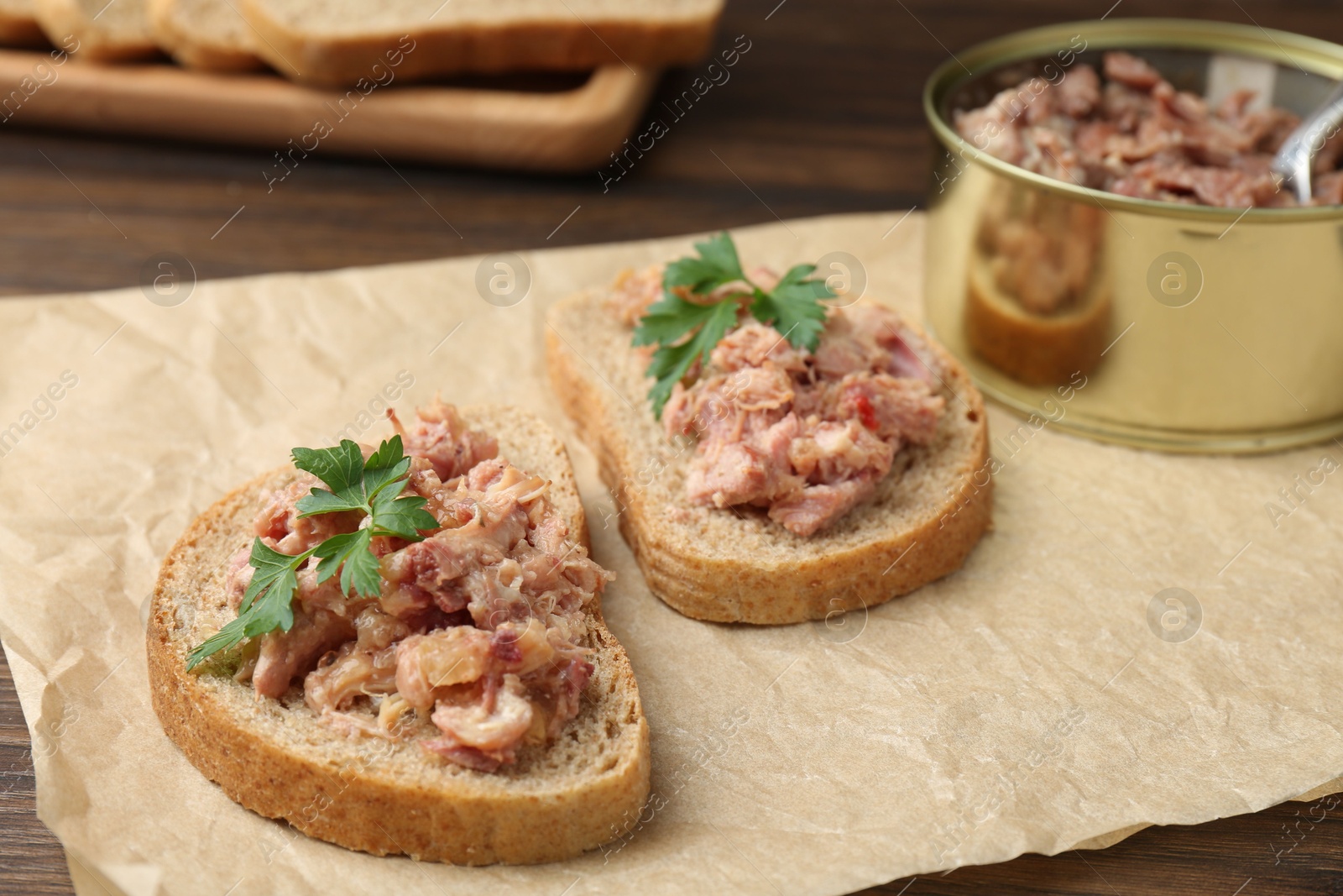 Photo of Sandwiches with canned meat and parsley on table, closeup