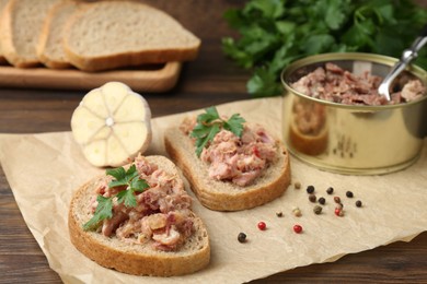 Sandwiches with canned meat, parsley, garlic and peppercorns on wooden table, closeup