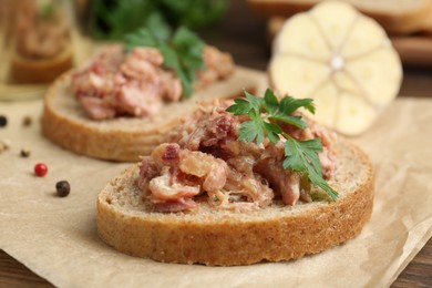 Photo of Sandwiches with canned meat, parsley, garlic and peppercorns on table, closeup