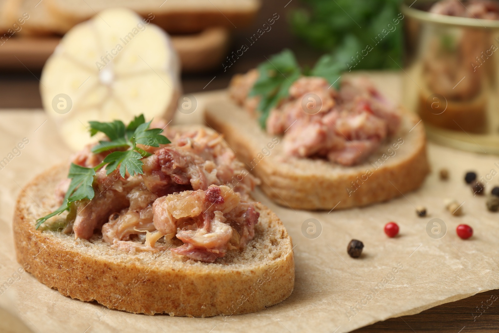 Photo of Sandwiches with canned meat, parsley, garlic and peppercorns on table, closeup