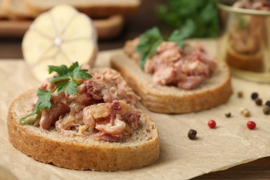 Photo of Sandwiches with canned meat, parsley, garlic and peppercorns on table, closeup