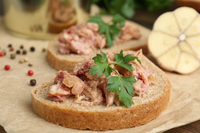 Photo of Sandwiches with canned meat, parsley, garlic and peppercorns on table, closeup