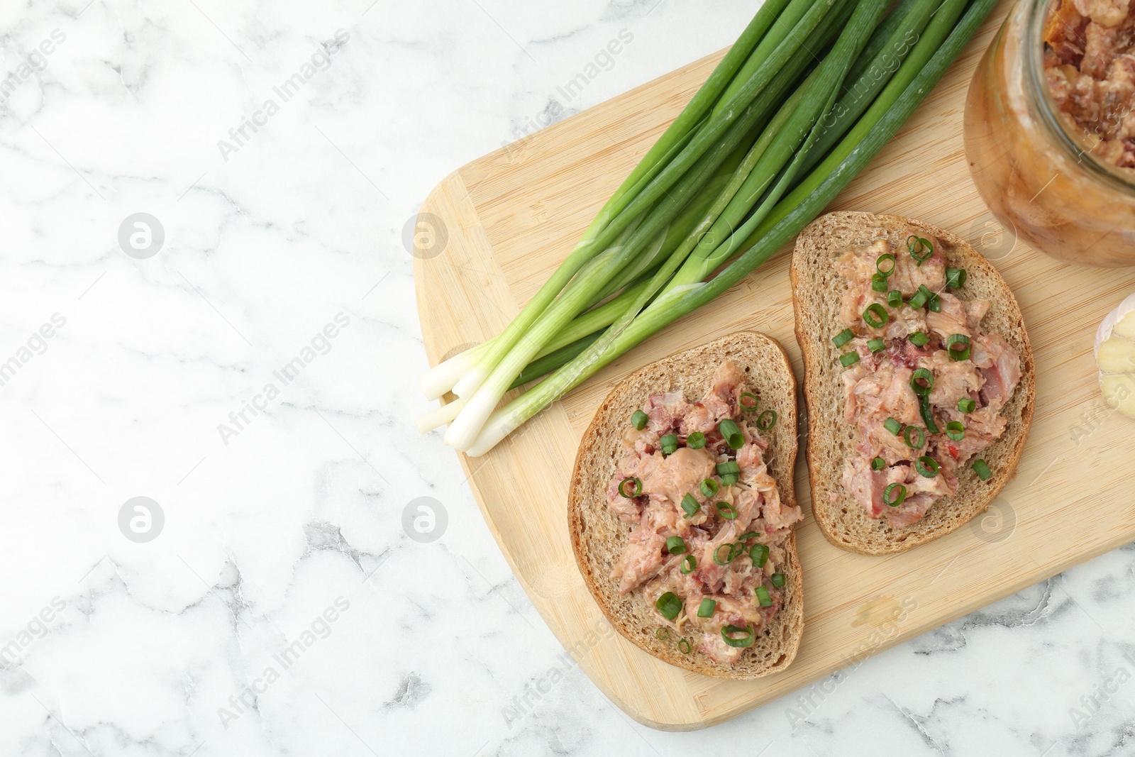 Photo of Sandwiches with canned meat and green onions on white marble table, top view. Space for text