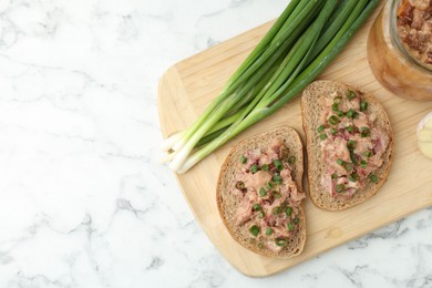 Photo of Sandwiches with canned meat and green onions on white marble table, top view. Space for text