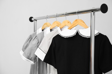 Photo of Maids' uniforms on clothing rack against grey background, closeup