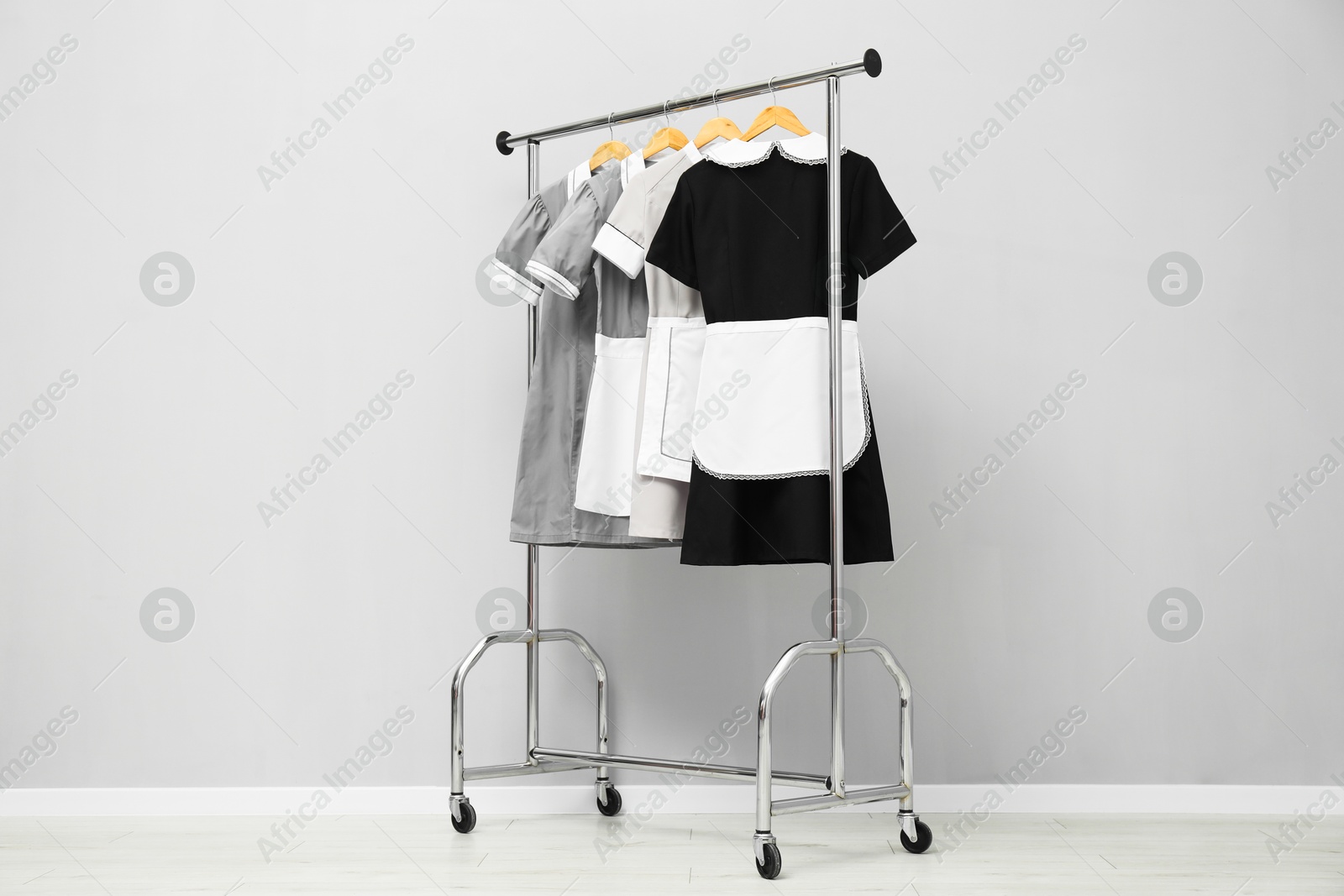 Photo of Maids' uniforms on clothing rack near grey wall indoors