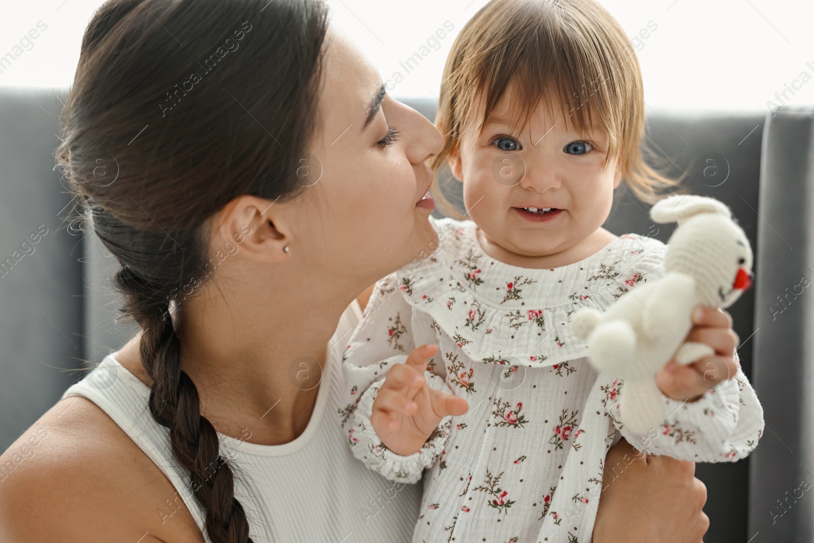 Photo of Beautiful young mother and her cute little baby with rabbit toy indoors