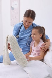 Doctor examining little girl on bed at hospital