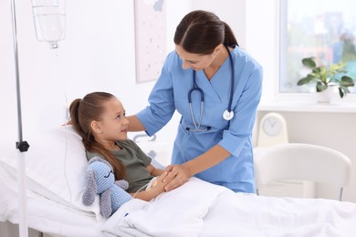 Doctor examining little girl on bed at hospital