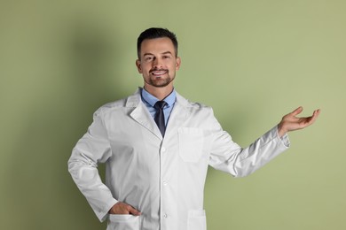 Smiling doctor pointing at something on olive background