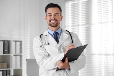 Photo of Smiling doctor with stethoscope and clipboard in clinic