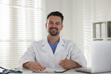 Photo of Smiling doctor working at table in clinic