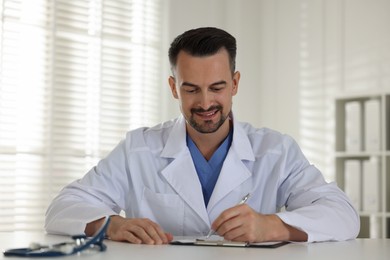 Photo of Smiling doctor working at table in clinic