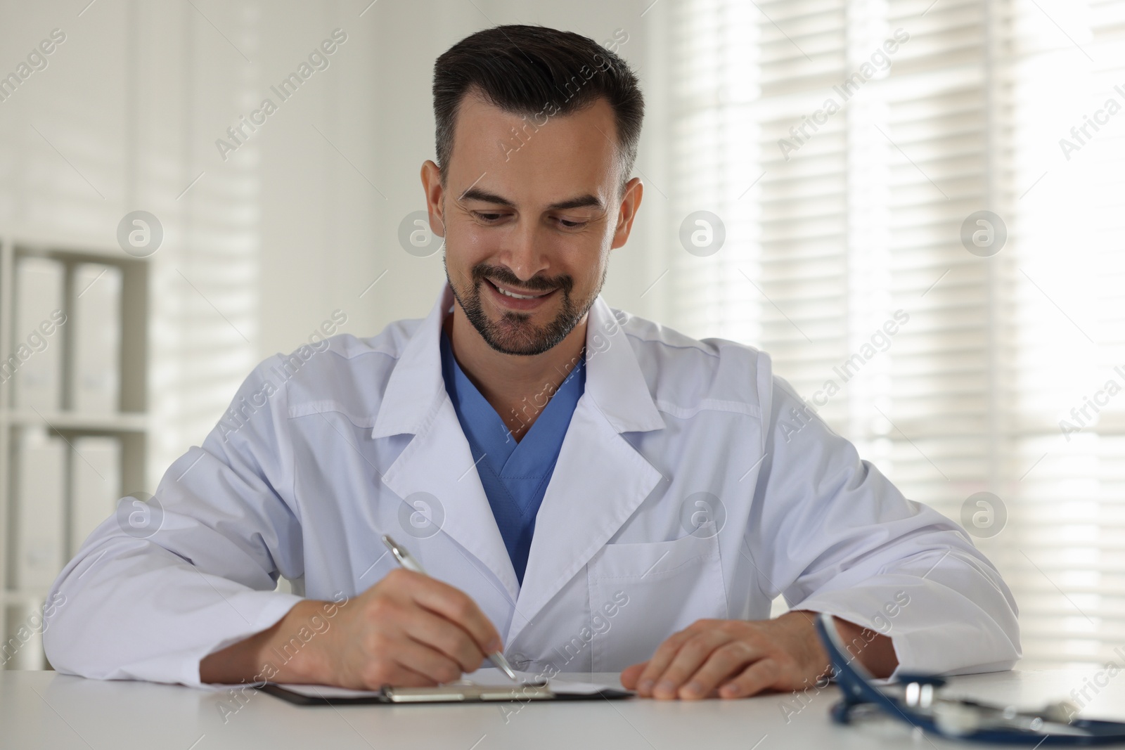 Photo of Smiling doctor working at table in clinic