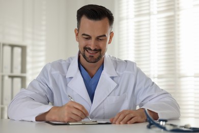 Smiling doctor working at table in clinic