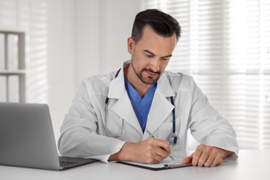 Photo of Doctor with clipboard at table in clinic