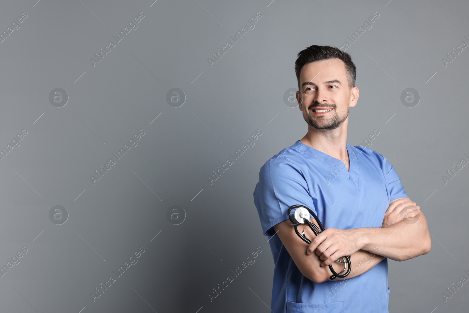 Photo of Smiling nurse with stethoscope on grey background, space for text