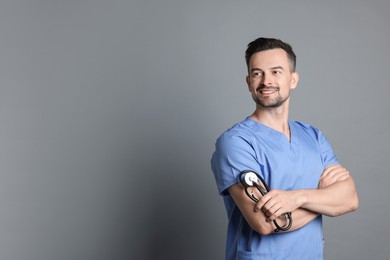 Smiling nurse with stethoscope on grey background, space for text