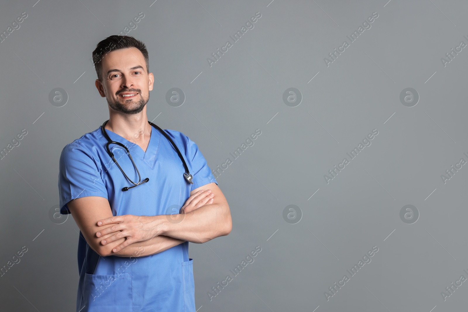 Photo of Smiling nurse with stethoscope on grey background, space for text