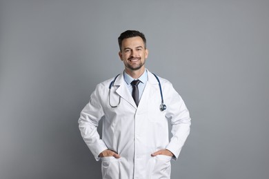 Photo of Smiling doctor with stethoscope on grey background