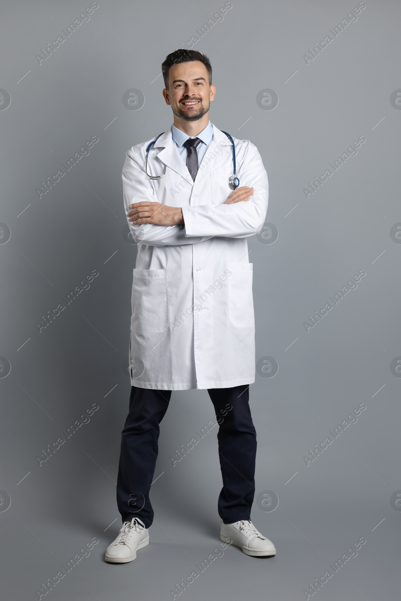 Photo of Smiling doctor with stethoscope on grey background