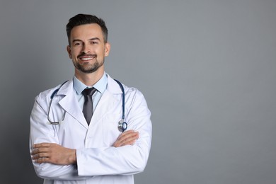 Smiling doctor with stethoscope on grey background, space for text