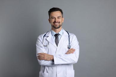 Photo of Smiling doctor with stethoscope on grey background