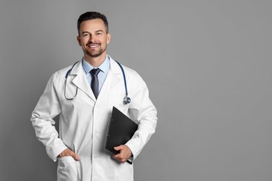 Smiling doctor with stethoscope and clipboard on grey background, space for text