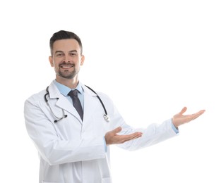 Smiling doctor with stethoscope pointing at something on white background