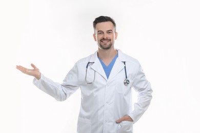 Photo of Smiling doctor with stethoscope pointing at something on white background