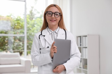 Smiling doctor with stethoscope and laptop in clinic