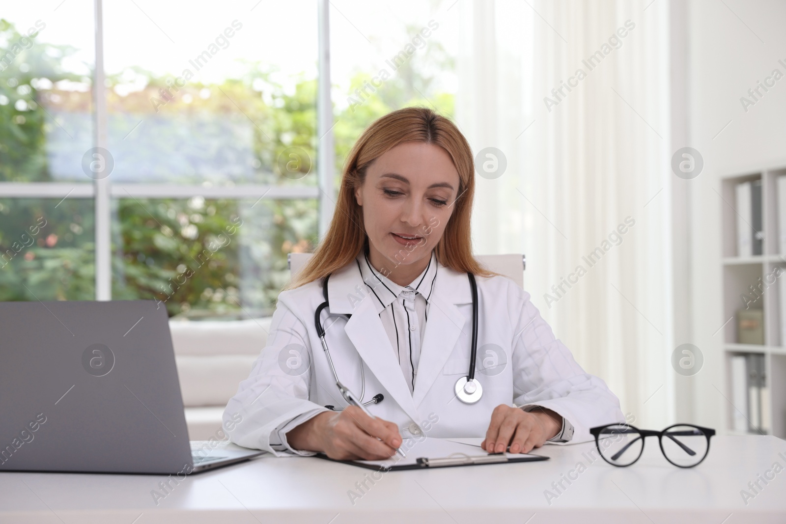 Photo of Doctor with clipboard at table in clinic