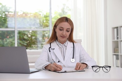 Doctor with clipboard at table in clinic