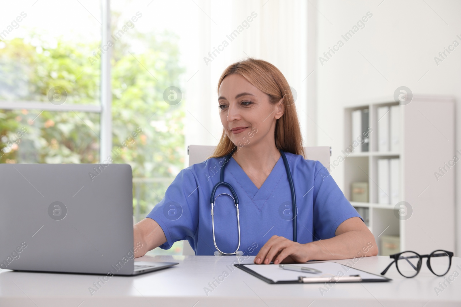 Photo of Doctor using laptop at table in clinic