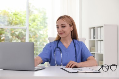 Photo of Doctor using laptop at table in clinic