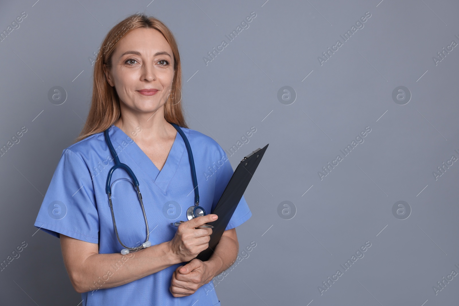 Photo of Doctor with stethoscope and clipboard on gray background