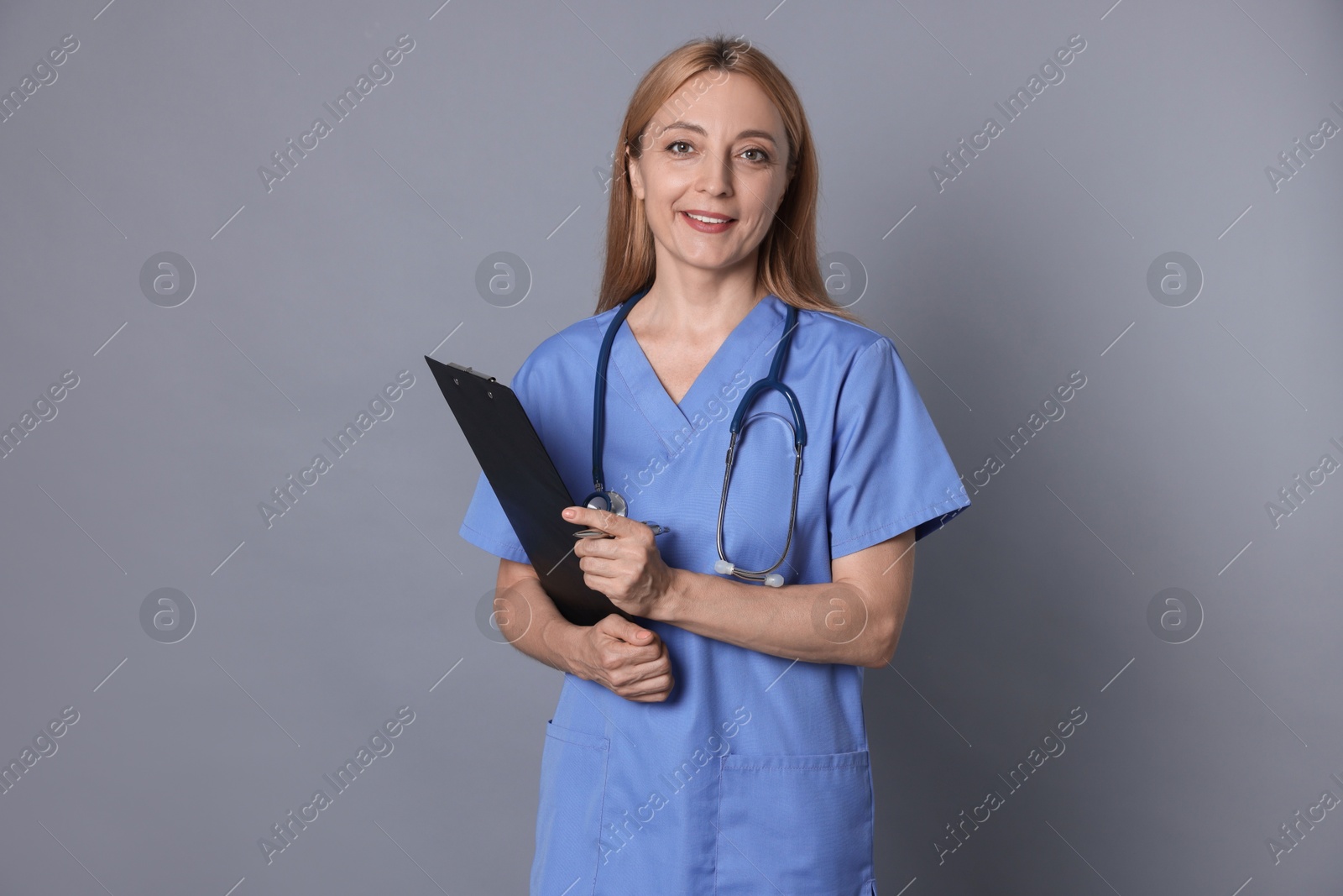 Photo of Doctor with stethoscope and clipboard on gray background