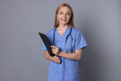 Doctor with stethoscope and clipboard on gray background