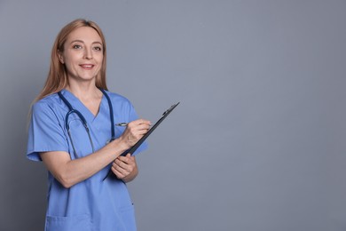 Doctor with clipboard writing notes on gray background, space for text