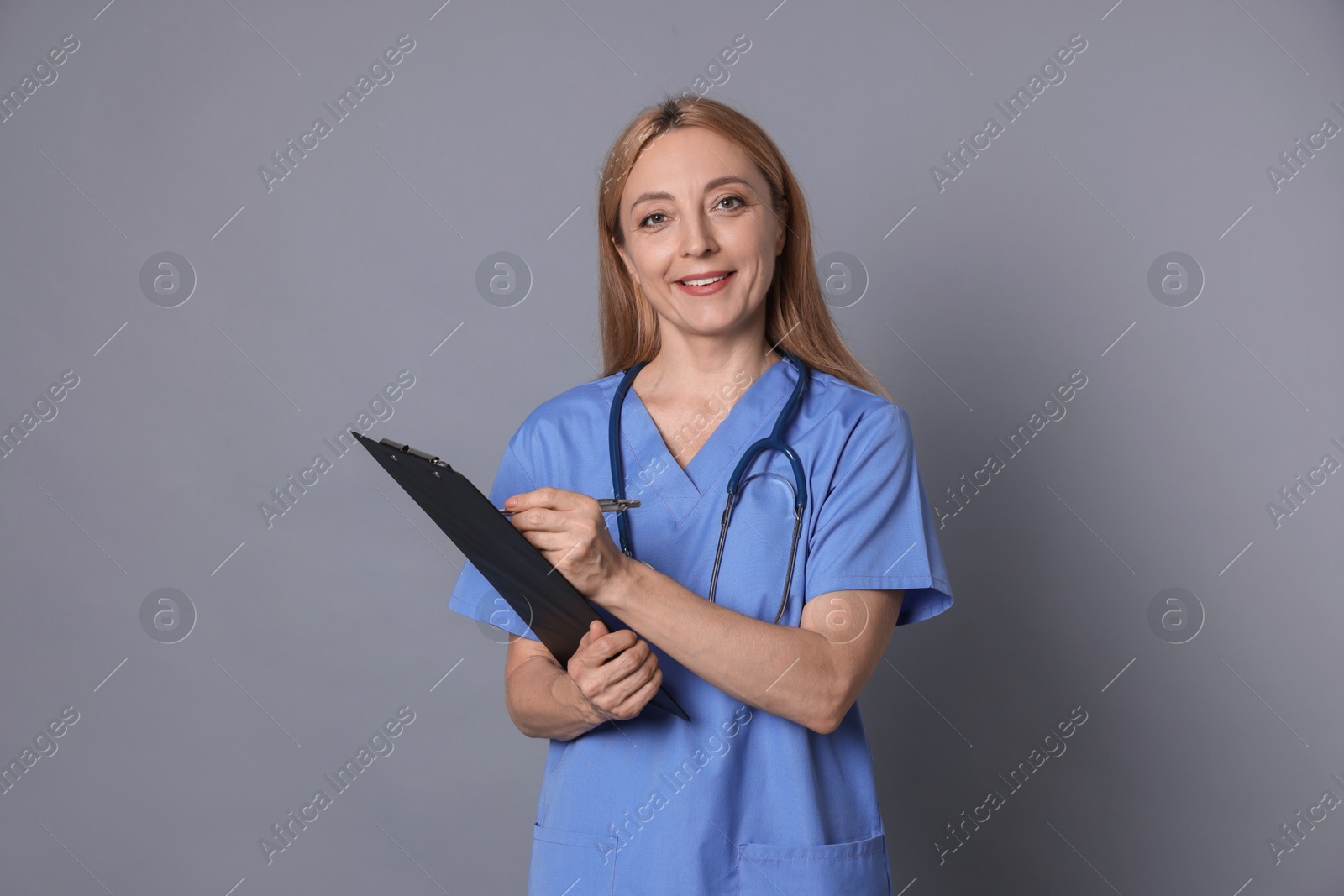 Photo of Doctor with clipboard writing notes on gray background