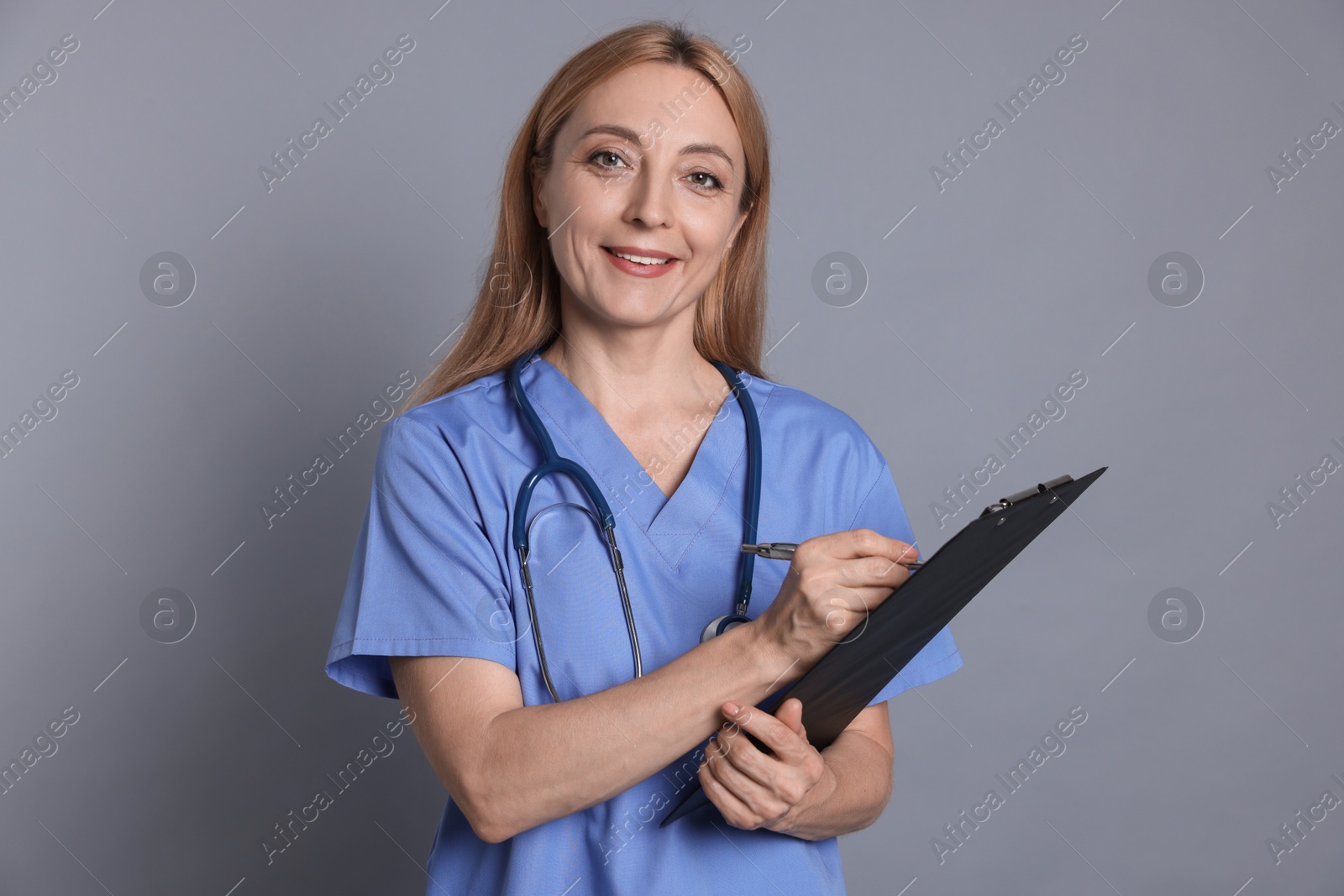 Photo of Doctor with clipboard writing notes on gray background