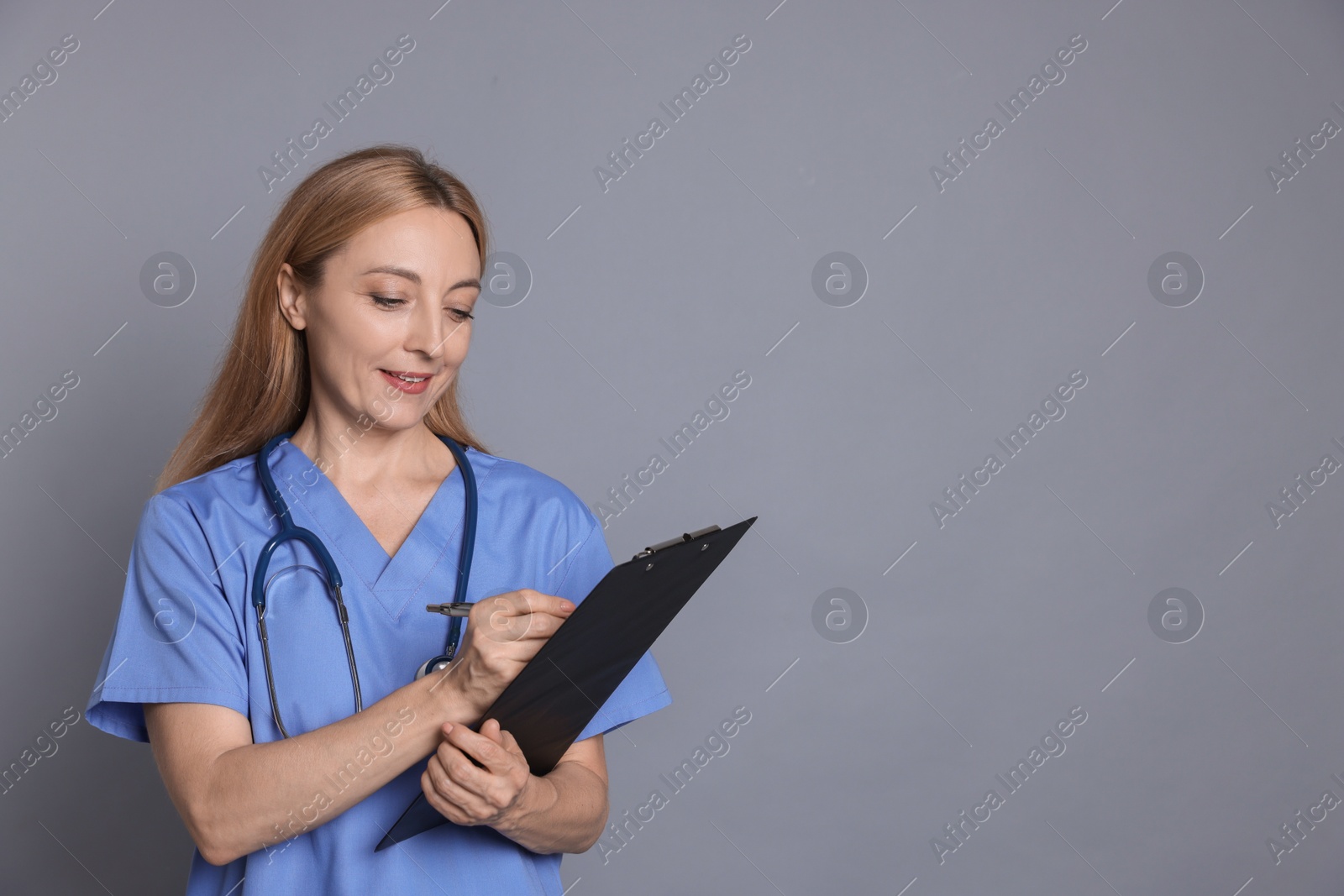 Photo of Doctor with clipboard writing notes on gray background, space for text