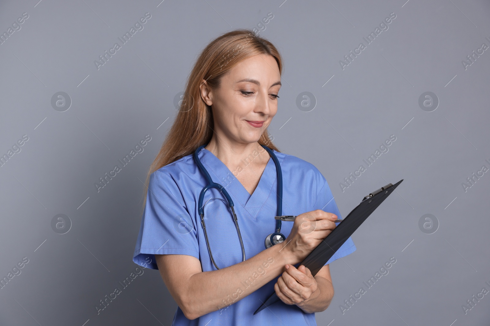 Photo of Doctor with clipboard writing notes on gray background