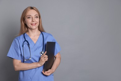 Photo of Doctor with stethoscope and laptop on gray background, space for text