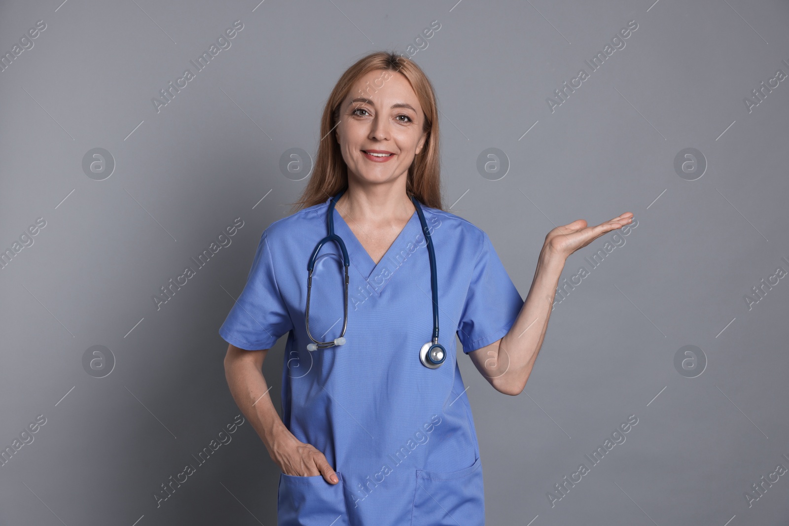 Photo of Doctor with stethoscope showing something on gray background