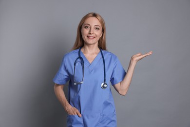 Photo of Doctor with stethoscope showing something on gray background