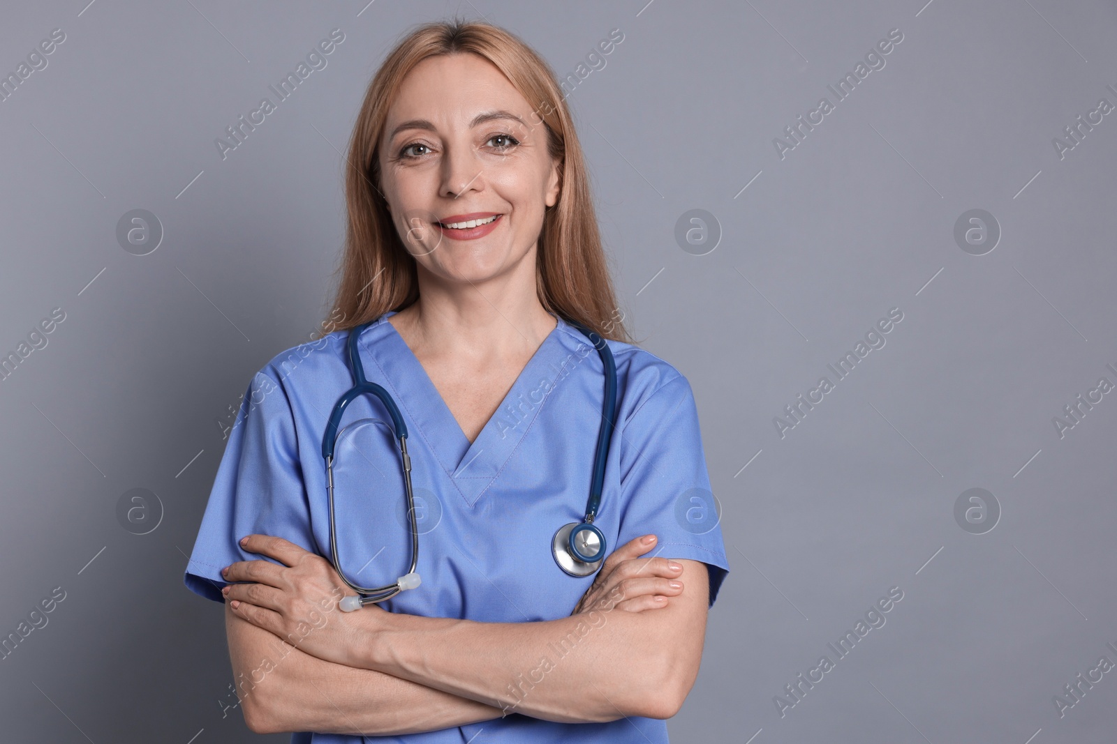 Photo of Smiling doctor with stethoscope on gray background